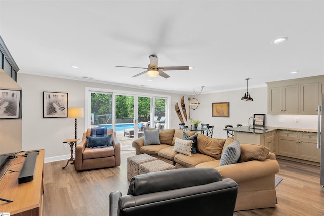 living room featuring crown molding, ceiling fan, and light wood-type flooring