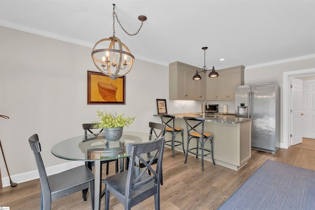 dining space with baseboards, a chandelier, ornamental molding, and light wood-type flooring
