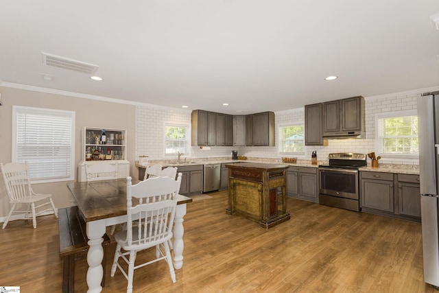 kitchen with decorative backsplash, visible vents, a sink, under cabinet range hood, and stainless steel appliances