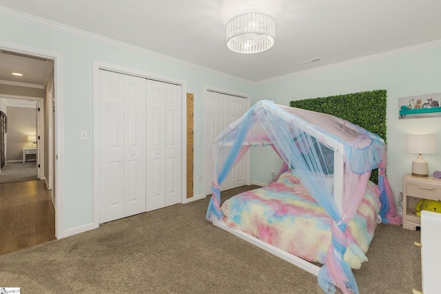 bedroom with an inviting chandelier, carpet floors, ornamental molding, and multiple closets
