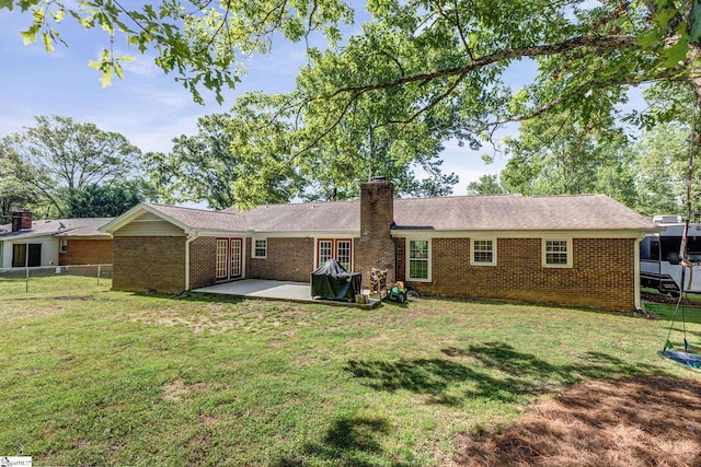 back of property featuring fence, a patio, a chimney, brick siding, and a lawn