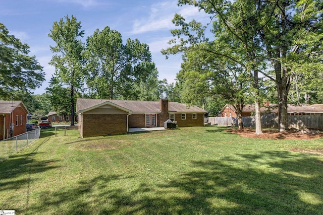 back of house featuring a patio, a fenced backyard, a chimney, brick siding, and a lawn