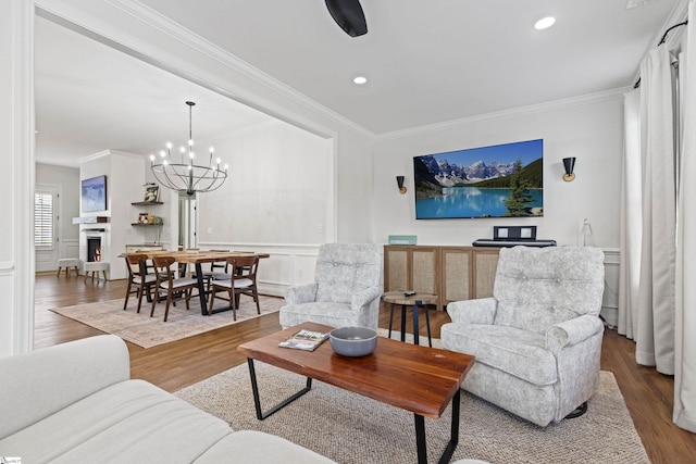 living room featuring crown molding, wainscoting, wood finished floors, a decorative wall, and recessed lighting