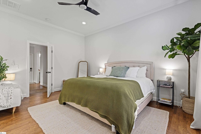 bedroom with visible vents, ornamental molding, baseboards, and wood finished floors