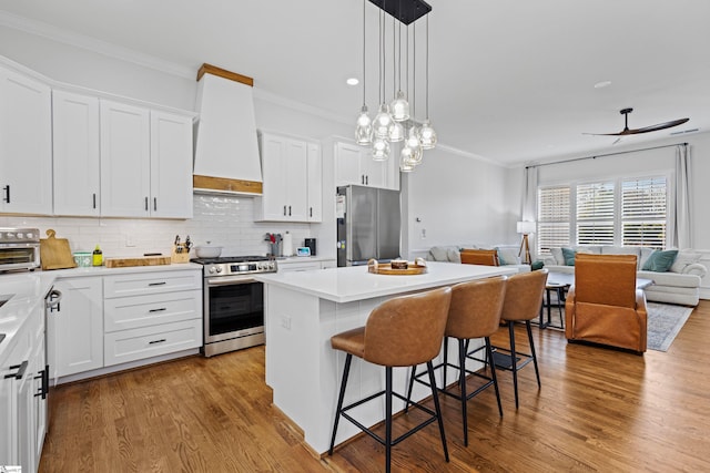 kitchen featuring crown molding, a breakfast bar, open floor plan, a center island, and appliances with stainless steel finishes