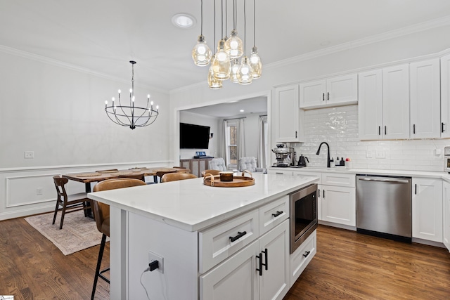 kitchen with a kitchen breakfast bar, crown molding, a sink, a chandelier, and stainless steel appliances