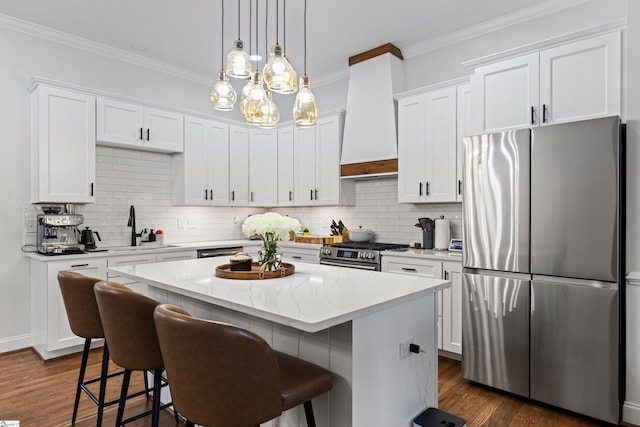 kitchen featuring appliances with stainless steel finishes, a sink, white cabinetry, a kitchen island, and custom exhaust hood