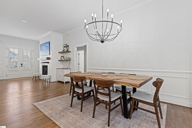 dining space featuring crown molding, a decorative wall, a chandelier, and a fireplace