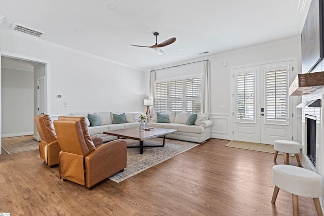 living room with crown molding, wood finished floors, and visible vents