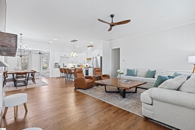 living room featuring crown molding, recessed lighting, ceiling fan with notable chandelier, and light wood-type flooring