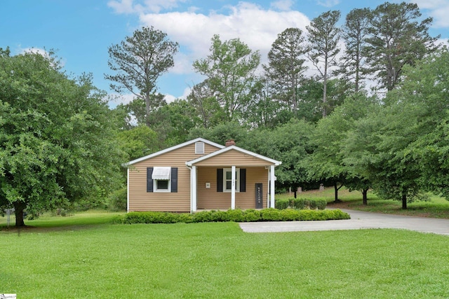 bungalow-style home with a chimney, a porch, and a front lawn