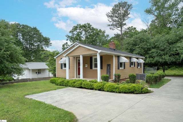 view of front facade with covered porch, a chimney, central air condition unit, and a front lawn