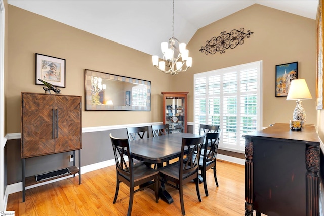 dining space with visible vents, baseboards, a chandelier, light wood-style flooring, and vaulted ceiling