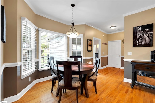 dining space with light wood-style floors, baseboards, and crown molding
