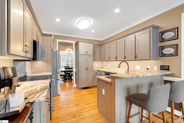 kitchen featuring a kitchen bar, a sink, a peninsula, ornamental molding, and stainless steel appliances