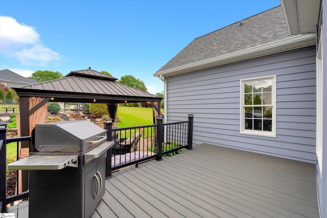 deck with grilling area, a gazebo, and a yard