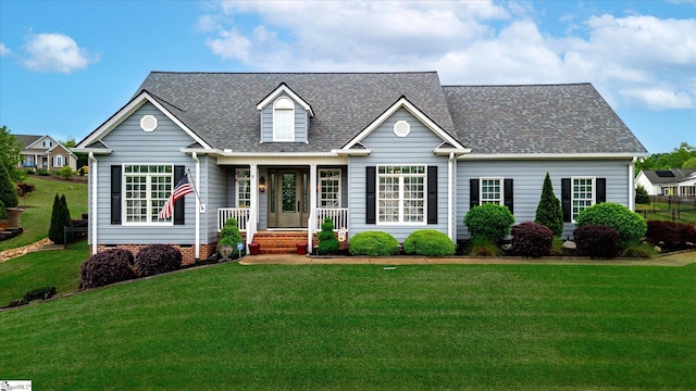cape cod home with roof with shingles and a front yard