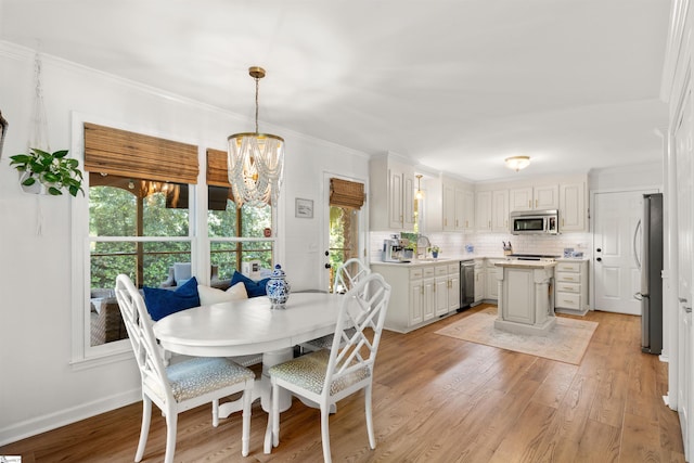 dining area with baseboards, ornamental molding, light wood-style flooring, and a notable chandelier