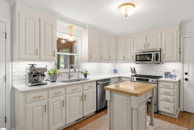 kitchen featuring white cabinetry, a sink, butcher block counters, stainless steel appliances, and light wood-style flooring