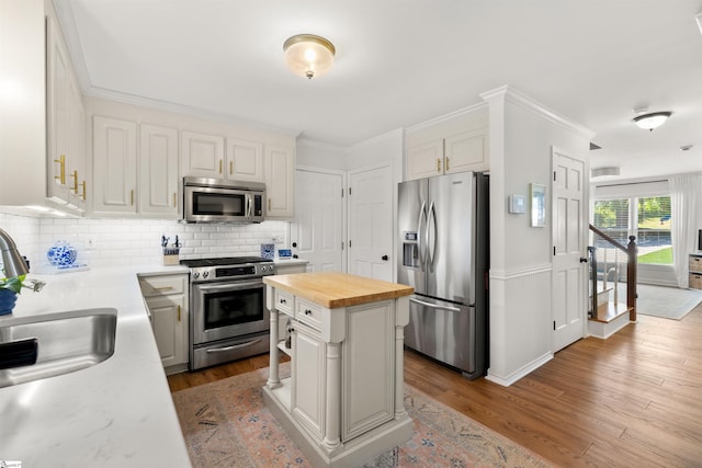 kitchen with decorative backsplash, dark wood-style flooring, butcher block counters, a sink, and stainless steel appliances