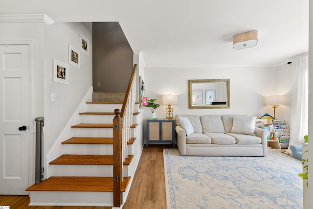 staircase with crown molding and wood finished floors