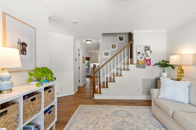 interior space featuring stairway, ornamental molding, wood finished floors, and visible vents
