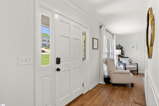 entrance foyer with crown molding, baseboards, and light wood finished floors