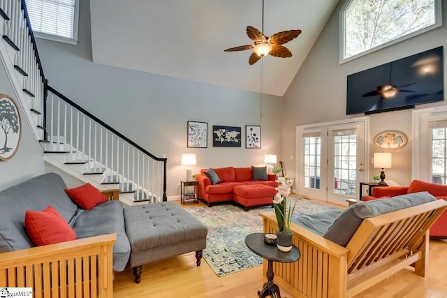 living room featuring wood finished floors, high vaulted ceiling, stairway, a ceiling fan, and a wealth of natural light