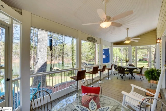 sunroom / solarium featuring a water view, a ceiling fan, outdoor dining space, and wood finished floors