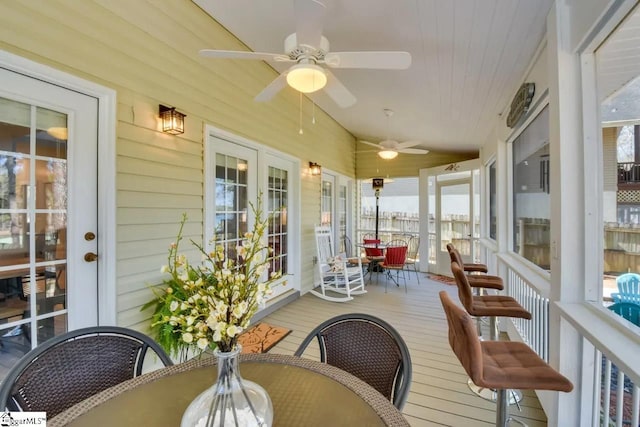 sunroom featuring a ceiling fan, french doors, and outdoor dining space