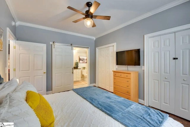 bedroom featuring a barn door, two closets, baseboards, wood finished floors, and ornamental molding