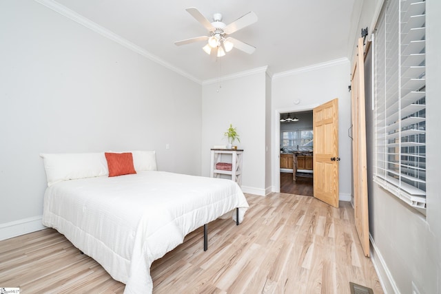bedroom featuring crown molding, baseboards, a barn door, and light wood-style floors