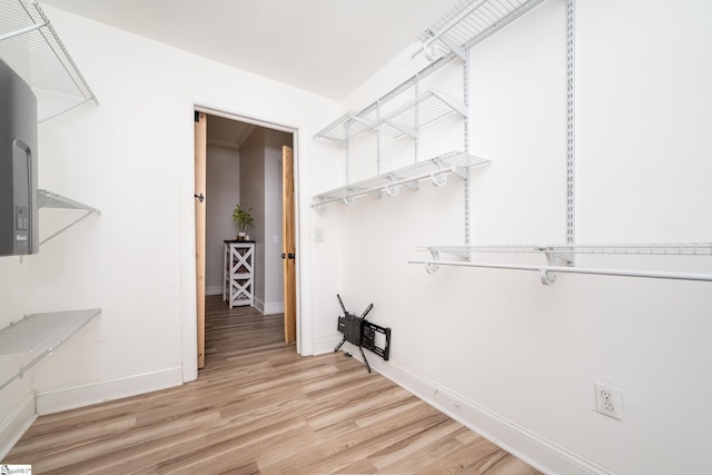 walk in closet with light wood finished floors