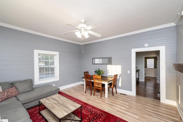 living room featuring visible vents, ornamental molding, baseboards, ceiling fan, and light wood-style flooring