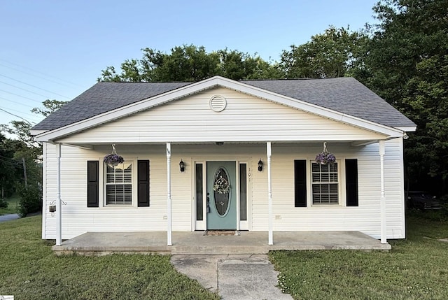 bungalow-style home featuring a shingled roof, a front lawn, and covered porch