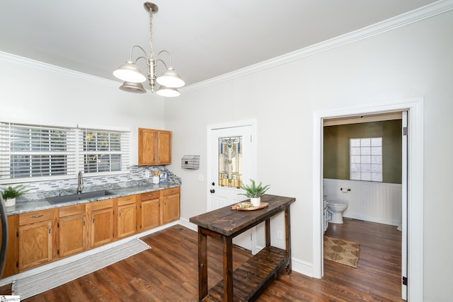 kitchen with a sink, brown cabinetry, a notable chandelier, and dark wood-type flooring