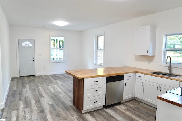 kitchen featuring a sink, light wood finished floors, butcher block countertops, a peninsula, and stainless steel dishwasher