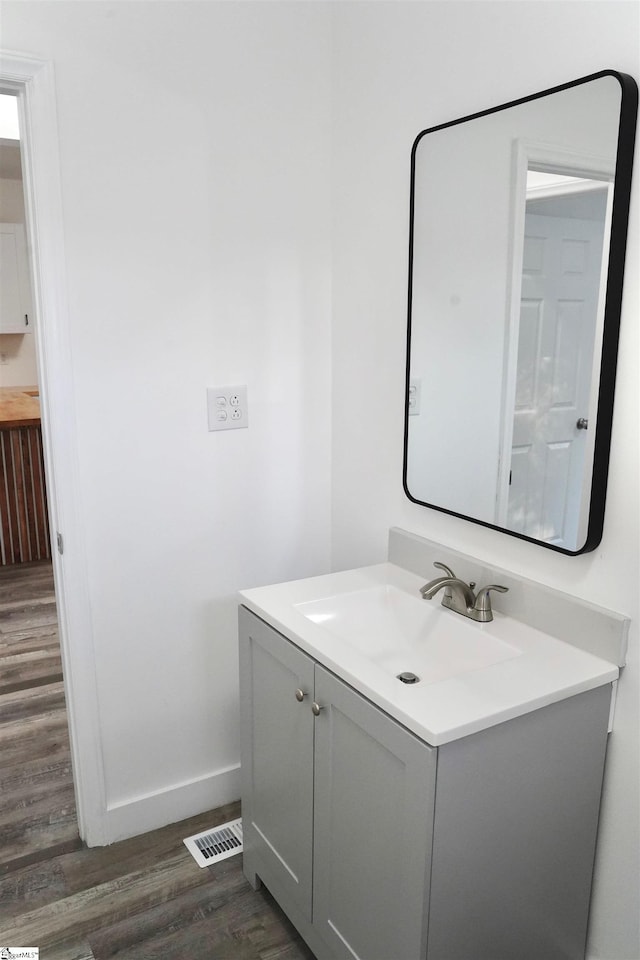 bathroom with baseboards, wood finished floors, visible vents, and vanity