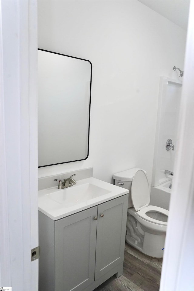 bathroom featuring vanity, tub / shower combination, wood finished floors, and toilet