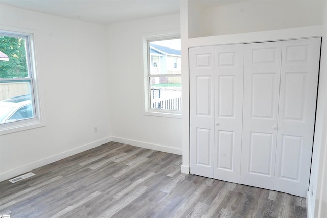 unfurnished bedroom with a closet, baseboards, visible vents, and light wood-type flooring