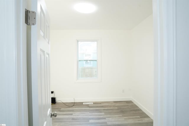 spare room featuring baseboards and wood finished floors