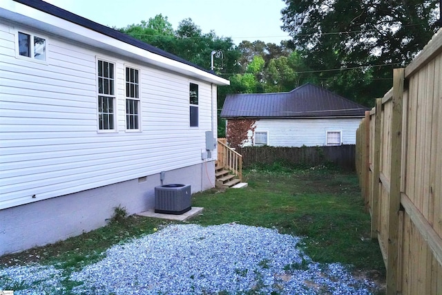 view of side of property featuring a fenced backyard, central AC, and crawl space