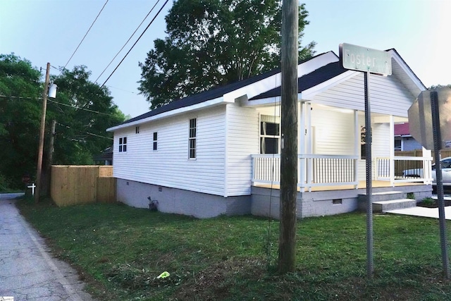 view of side of home with a lawn, covered porch, and crawl space