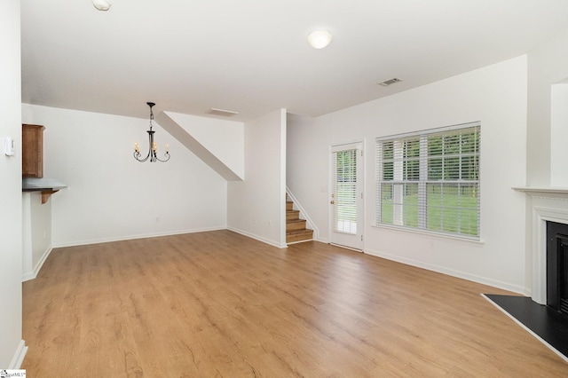 unfurnished living room with stairway, visible vents, light wood-style floors, and a chandelier