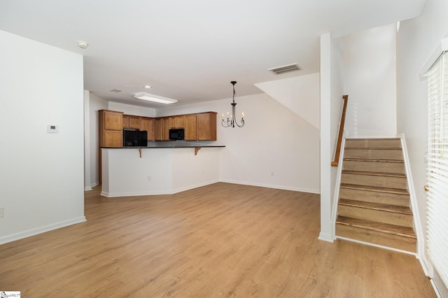 unfurnished living room featuring visible vents, an inviting chandelier, stairs, baseboards, and light wood finished floors