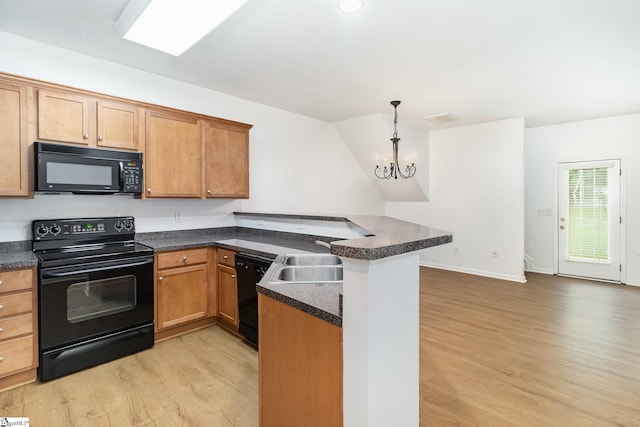 kitchen featuring dark countertops, a sink, a chandelier, a peninsula, and black appliances
