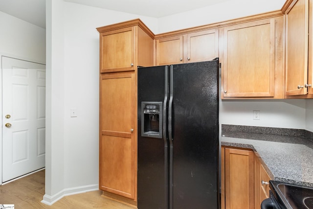 kitchen with black refrigerator with ice dispenser, baseboards, dark stone counters, electric range oven, and light wood-style flooring