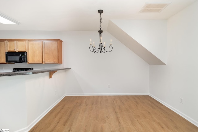 unfurnished dining area featuring visible vents, baseboards, light wood-type flooring, a chandelier, and vaulted ceiling