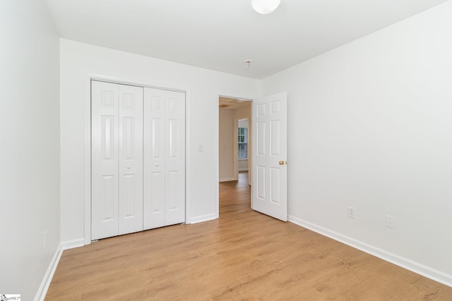 unfurnished bedroom with a closet, baseboards, and light wood-type flooring