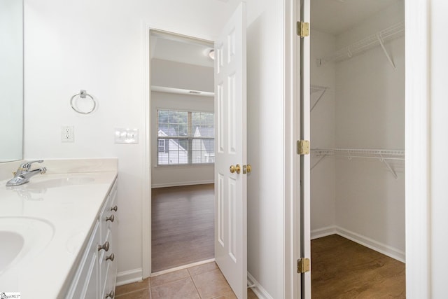 bathroom with a sink, baseboards, and double vanity